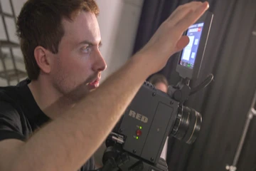 a fredonia student operates a camera in the tv production studio