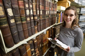 photo of student Rebekah Denz next to a stack of library books