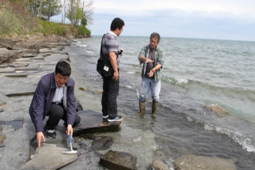 geology students examines rocks along a beach