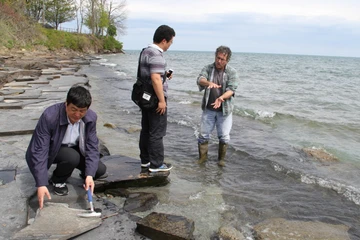 geology students examine rocks along a local beach