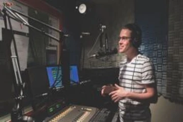 a student in the radio station studios talking live on the air on WCVF radio