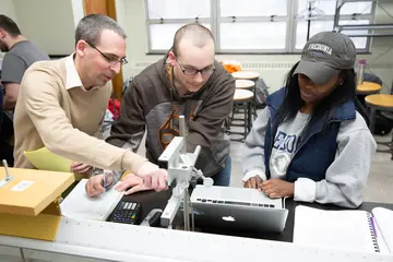 a fredonia professor points to a computer while advising a student