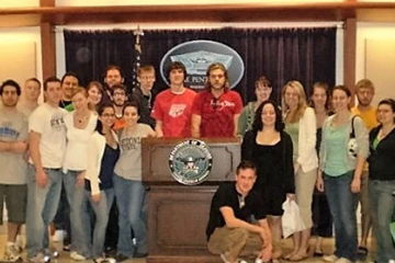 politics and international affairs students pose next to a podium at a government building 