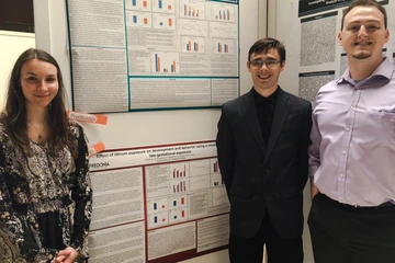 psychology students pose in front of the research presentation posters