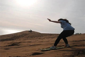 a student "surfs" the sand on a study abroad trip 