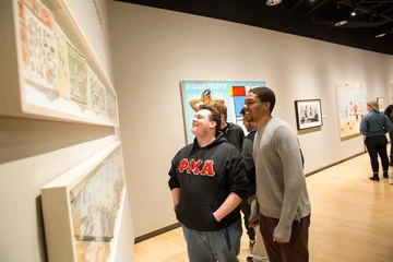 students look at art pieces during a gallery opening