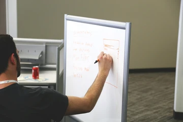 a man writes notes on a whiteboard