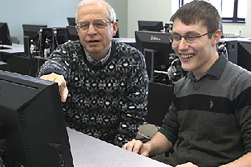 Professor working with CIS student at a computer.