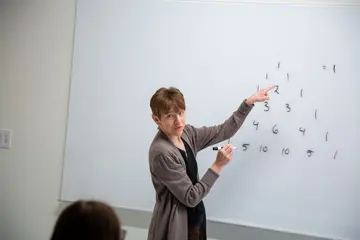 a professor explains a math problem to students. major in mathematics, mathematics major, mathematics degree, degree in mathematics, math degrees.