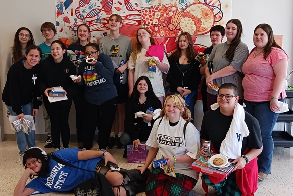 North Collins students gather for a photo in front of the SUNY Fredonia Science Center mural
