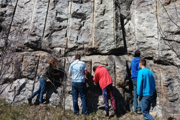 a group of students analyze a rock formation