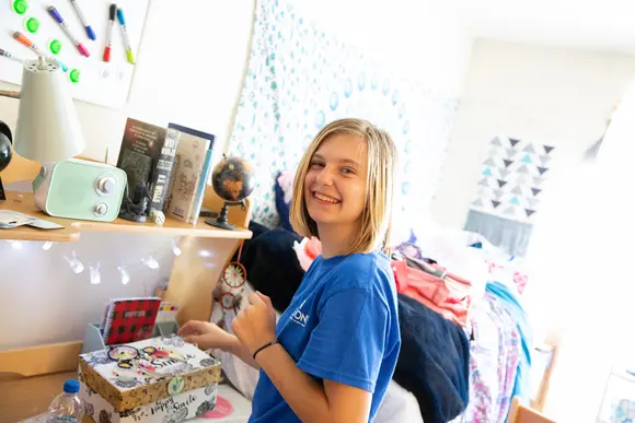 a student smiles as she moves into her residence hall during move-in weekend