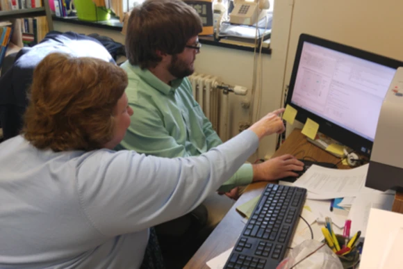 professor pointing at computer as student watches
