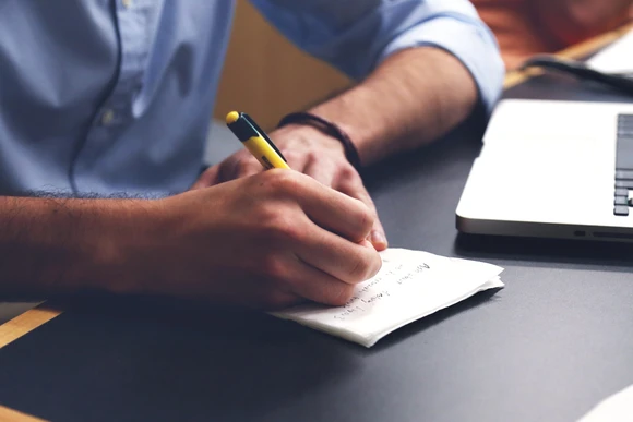 person writing at a desk. writing degree, writing programs in new york