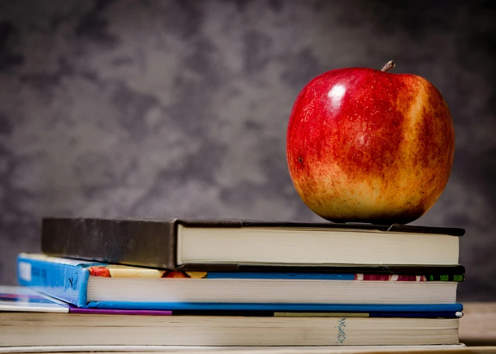An apple on a pile of books representing educational leadership for prospective graduate students.  