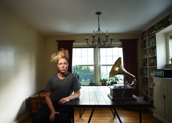 Staged photograph of poet Meg Day's hair being blown by a gramophone across the table.. 