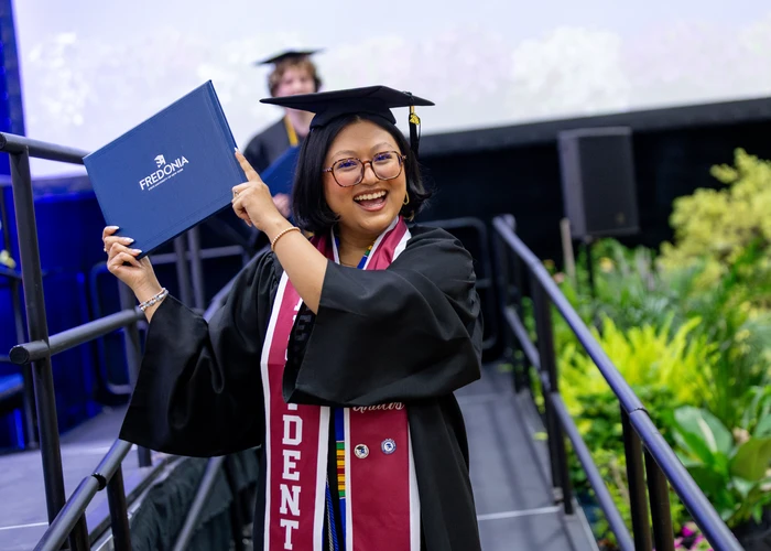 Student holding up diploma case at commencement