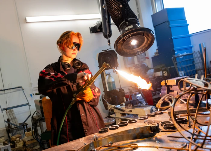 Fredonia student working with a blowtorch in the studio