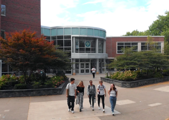 Fredonia student walking across campus on a spring day, low tuition, best SUNY schools