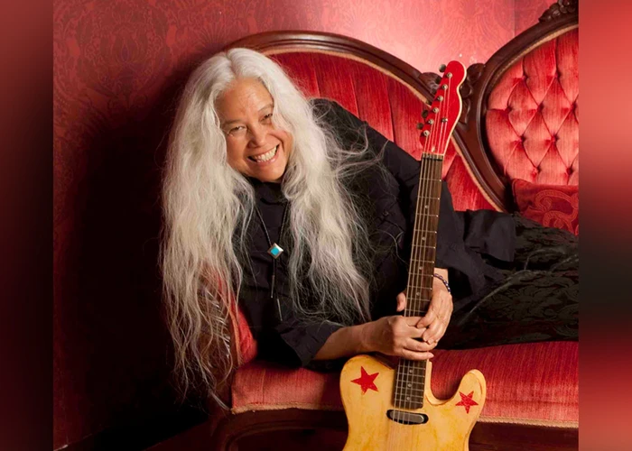 June Millington on a couch with a telecaster-style guitar