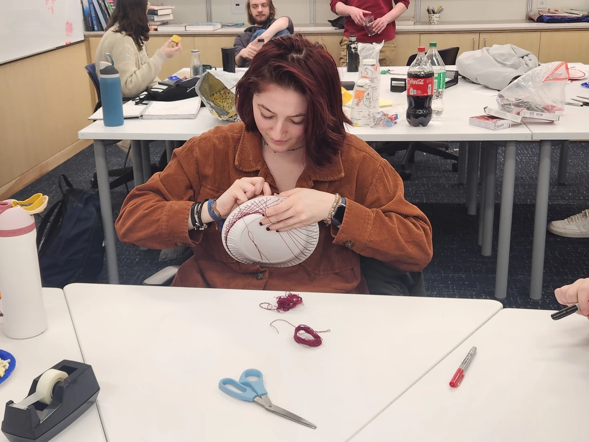 Student making string art on a paper plate