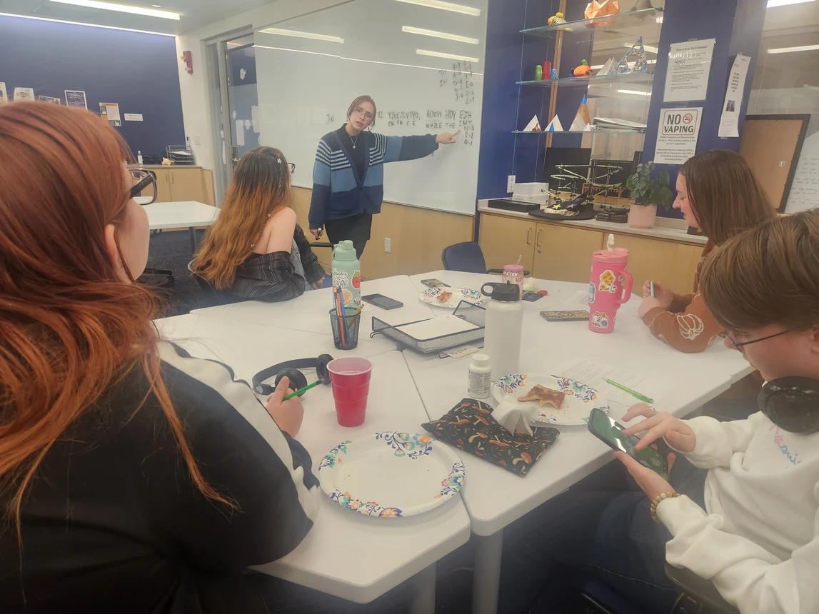 Students looking at another student who is pointing at a whiteboard