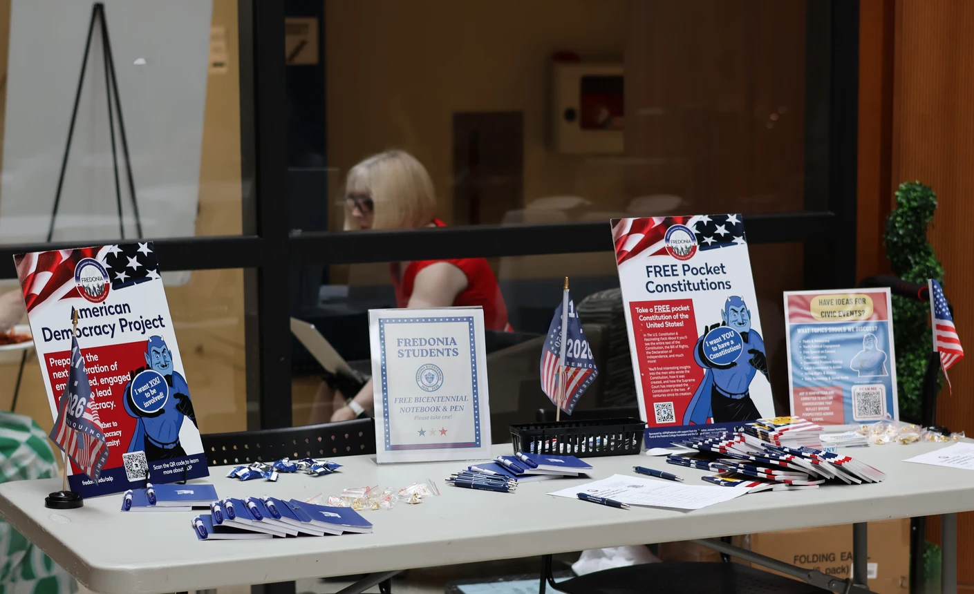 An ADP welcome table is filled with free pens, notebooks, and copies of the Constitution for attendees to take.