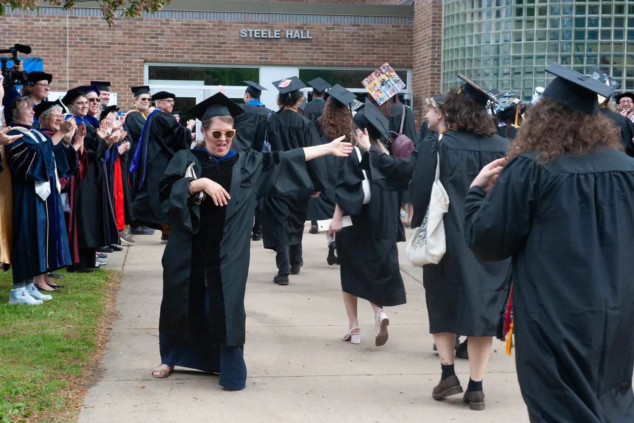 Faculty member gives a passing grad a high-five