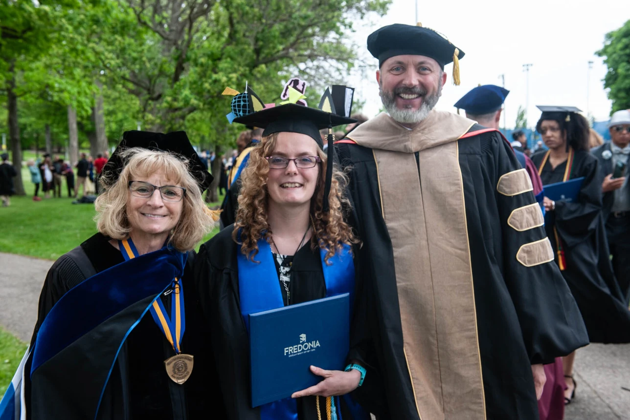 Graduate posing with faculty members
