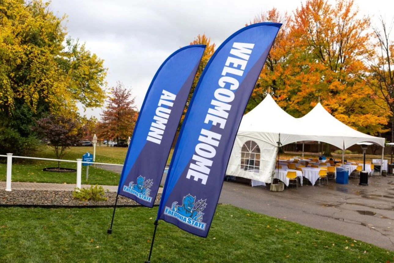 Blue flags with words welcome home alumni