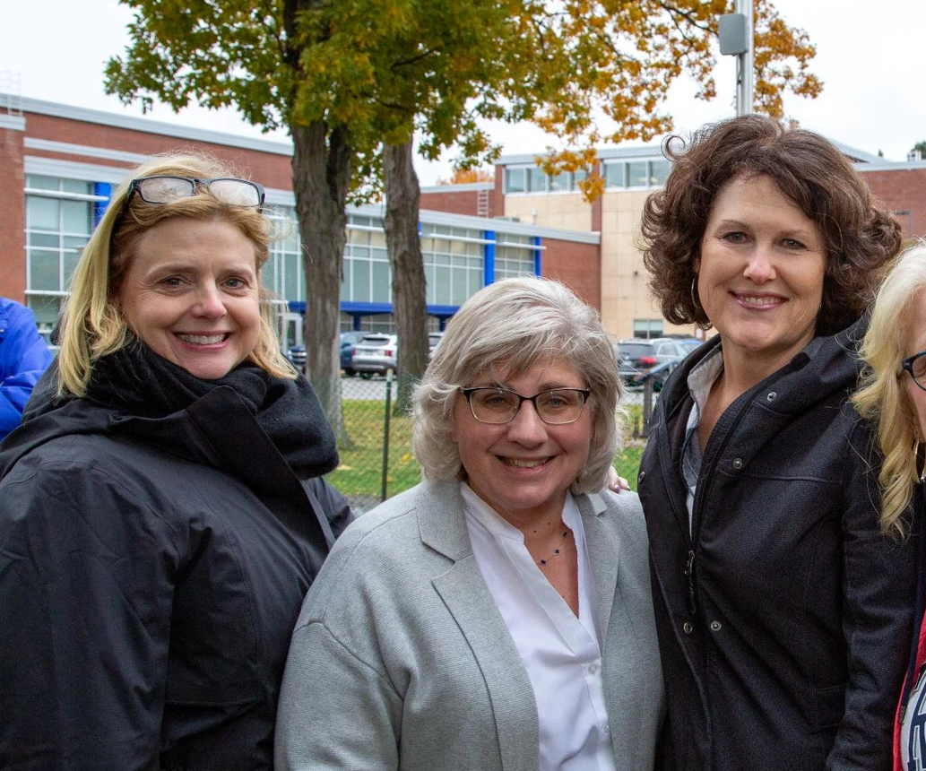 Four women smiling in outdoor setting