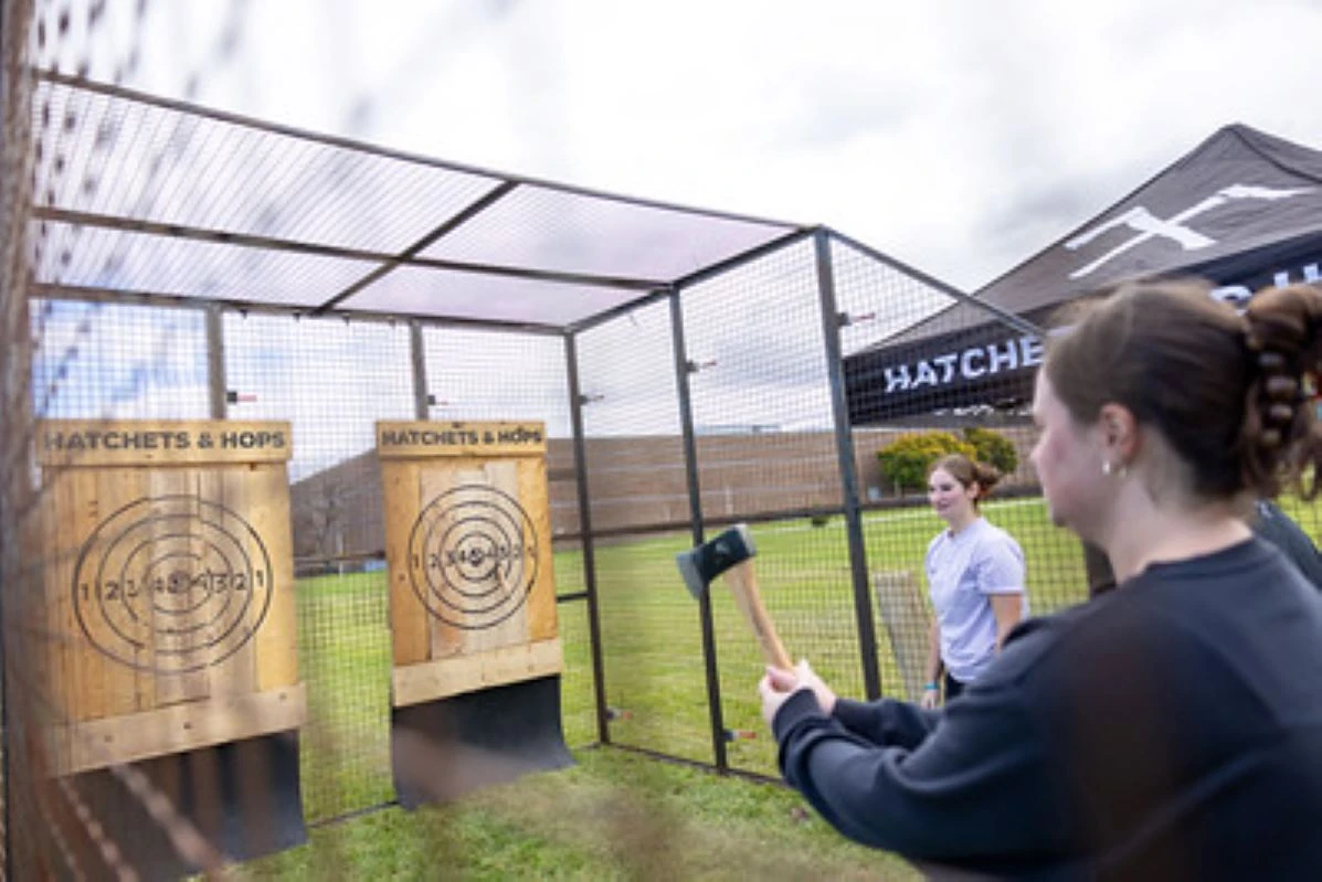 Woman aiming axe at wooden target