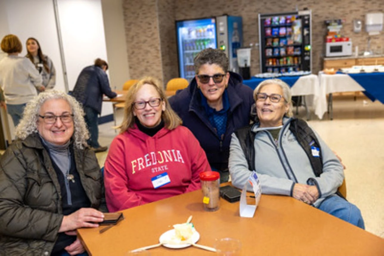 Four women pose at a table