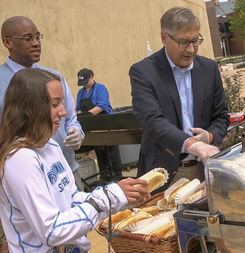 People adding toppings to hot dogs 