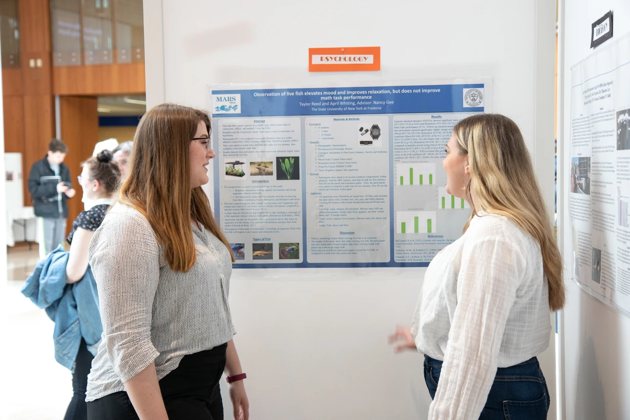 Students discuss research poster at OSCAR 2019.