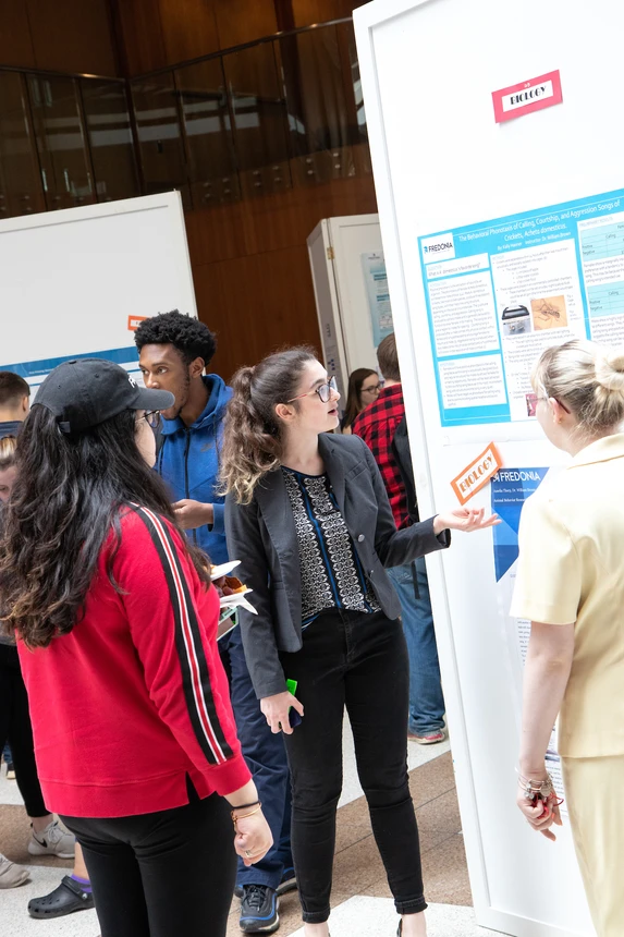 Students discuss research poster at OSCAR 2019.