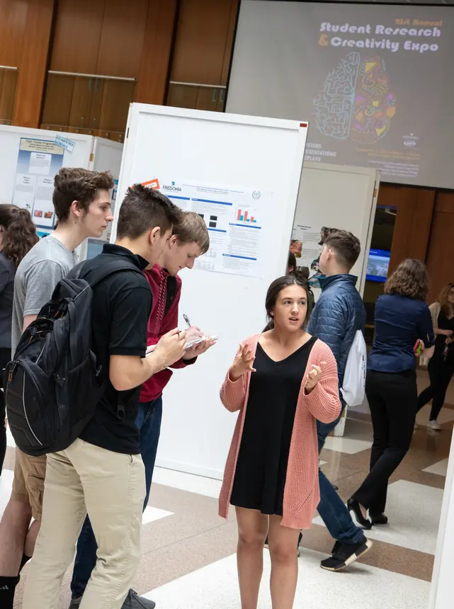 Students discuss research poster at OSCAR 2019.