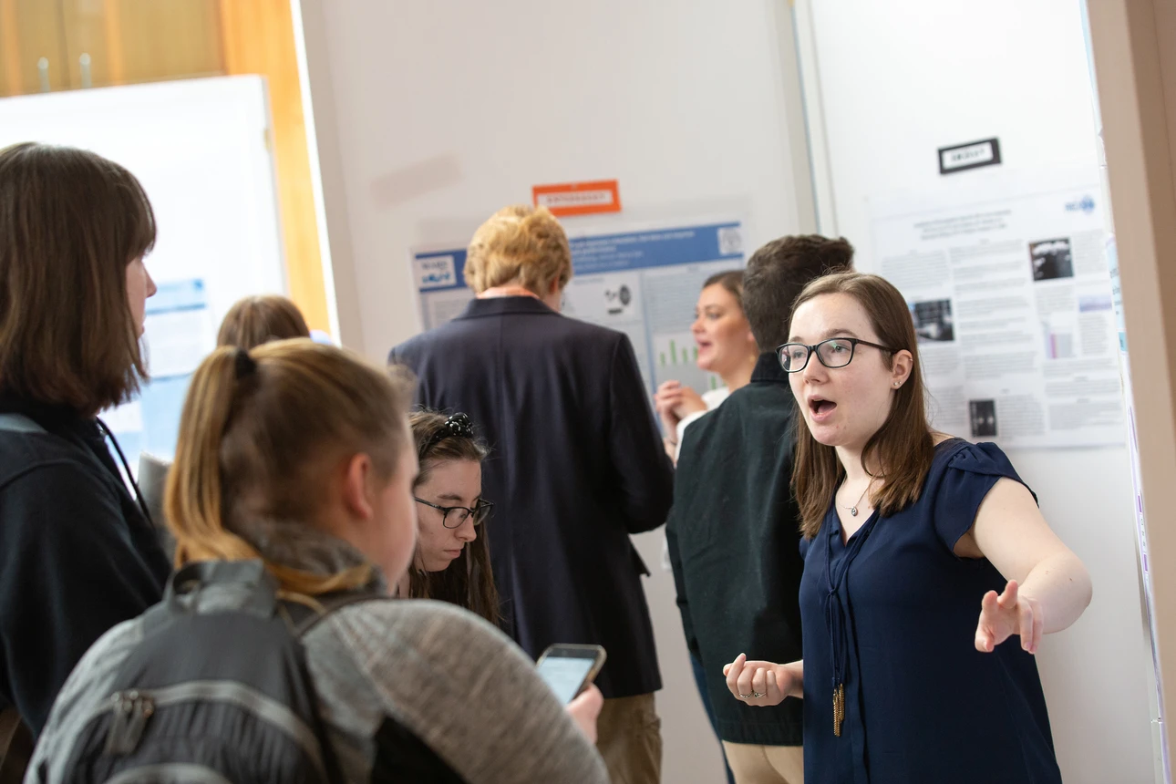 Students discuss research poster at OSCAR 2019.