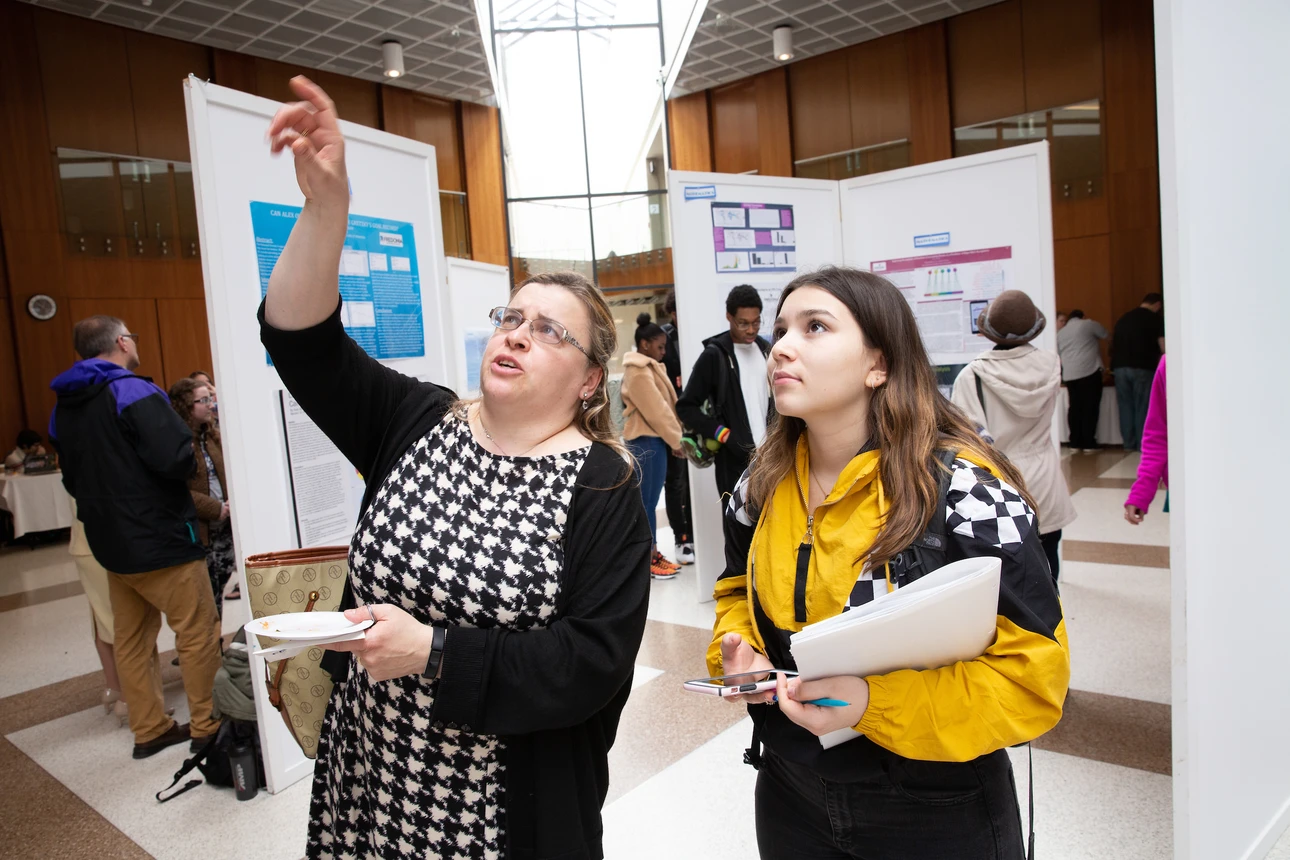 Student and professor discuss research poster at OSCAR 2019.