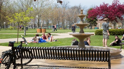 students sit in the grass near the fountain outside Williams Center