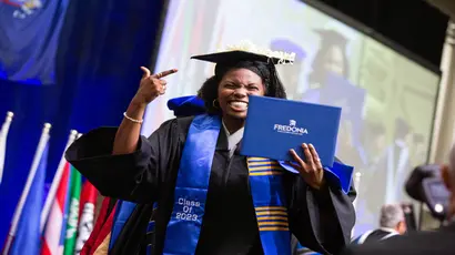 Excited student walking across the stage with diploma at graduation