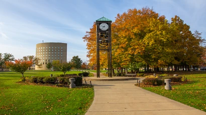 Looking into the Fredonia campus from above, seeing the clock tower and budding trees