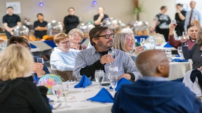 People at tables toasting with a beverage 