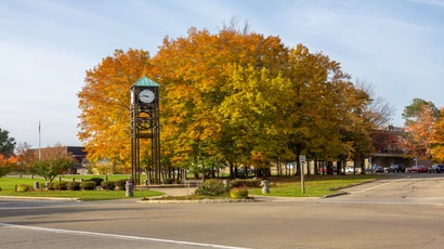 View of the clock tower and fall foliage on the trees, looking toward campus