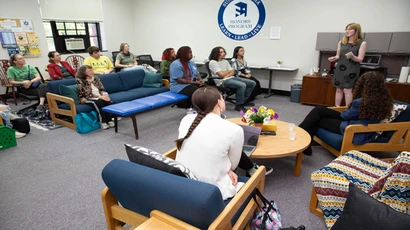 A student stands in front of a small gathering giving a presentation in the Honors Lounge.