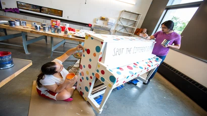 Two students paint a piano for the Street Piano Project.