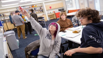 student pointing at a whiteboard where a math problem is written
