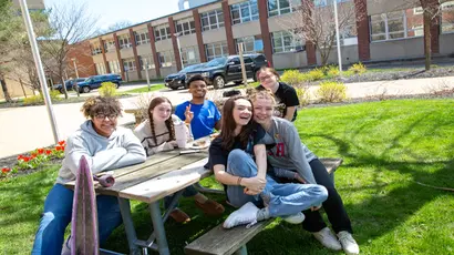 Fredonia students enjoying a gorgeous spring day around a picnic table 
