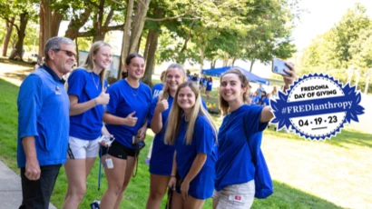 students in blue shirts taking a selfie, fredlanthropy logo