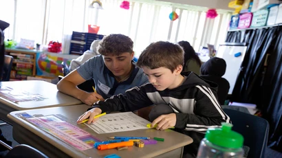 Fredonia student in a childhood education classroom working with a student. 